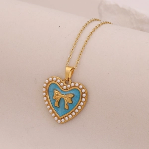 Detail of vintage gold heart pendant with blue enamel, bow, and pearl border