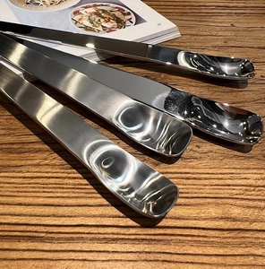 Detail view of four polished stainless steel dessert spoons on a rustic wooden table