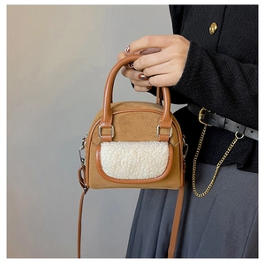 Close-up of brown suede handbag featuring white faux fur trim and elegant metal hardware detail