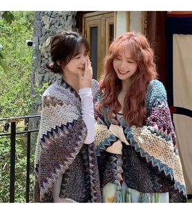 Outdoor model wearing colorful ethnic knitted ponchos with fringes and geometric patterns