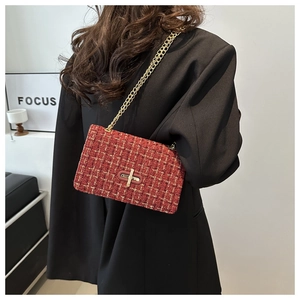 Détail du sac à bandoulière en tweed rouge avec chaîne dorée sur un blazer noir