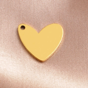 Polished gold heart pendant necklace on silk fabric, minimalist stainless steel jewelry