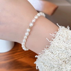 Close-up of minimalist natural freshwater pearl bracelet with 14K gold bead on wrist