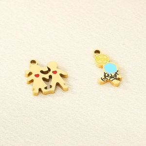 Macro detail of gold stainless steel heart boy girl and astronaut enamel charms