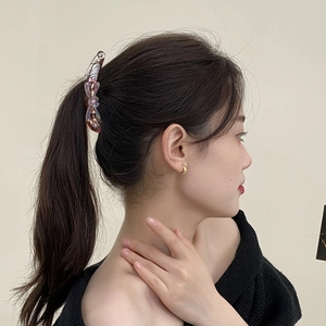 Elegant purple three-petal flower banana clip and gold hoop earrings on female model