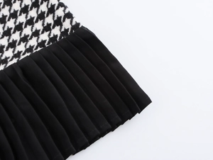 Détail du tissu à motif pied-de-poule et de la bordure plissée noire de la jupe