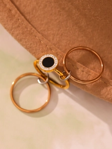 Gros plan d'un ensemble de bagues dorées avec disque noir et pavé de zircons cubiques