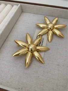 Detailed view of large gold flower earrings with mirror finish in jewelry storage box