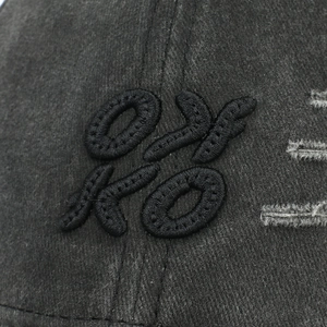 Close-up of OYKO embroidery and distressed torn detail on vintage washed baseball cap