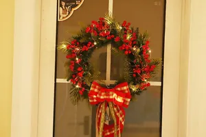 Close-up of Christmas wreath with red berries, pine needles, and glowing LED lights