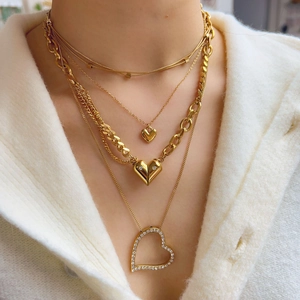 Close-up of layered gold heart necklaces with zircon stones worn by a model