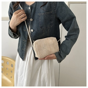 Close-up of mini hand-woven straw crossbody bag in cream white with woven strap