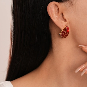 Détail d'une boucle d'oreille goutte vintage avec émail rouge et filigrane d'or