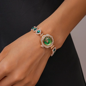 Macro view of vintage gold quartz watch with green gems and crystals on a female wrist