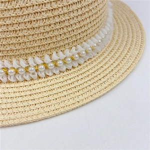 Détail d'un chapeau de paille avec dentelle blanche et perles avec fil doré