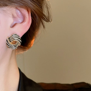 Detailed close-up of a vintage golden spiral stud earring with sparkling white rhinestones
