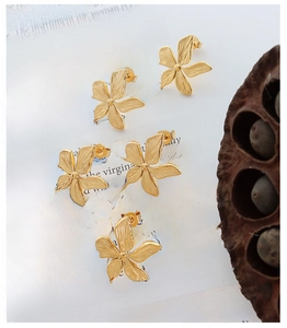 Detailed view of gold petal earrings with brushed metal texture on a vintage book