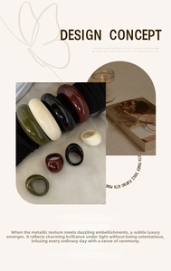 Close-up of minimalist resin rings and chunky bangles in emerald, cream, and burgundy