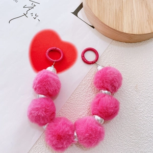 Detailed view of pink plush pom-poms with pearl beads chain and pink metal ring clasps