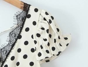 Close-up of polka dot dress featuring black lace trim and puffed sleeve detail
