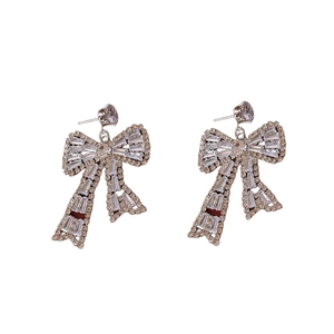 Elegant rose gold bow earrings set with sparkling rhinestones on a white background
