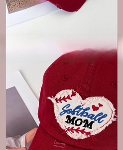 Detailed view of Softball MOM heart embroidery on distressed red cotton baseball cap