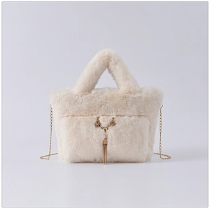 Detail of cream faux rabbit fur handbag featuring a golden chain and metal deer tassel