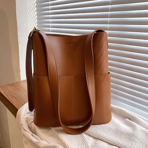 Braune Leder-Eimertasche mit Fronttasche auf einem rustikalen Fensterbrett aus Holz präsentiert