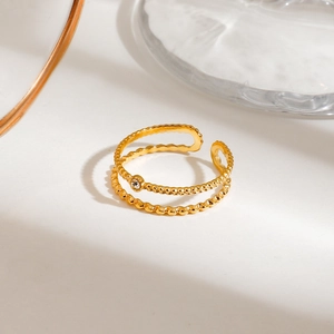 Detail of a double-layered gold stainless steel ring featuring a central zircon stone