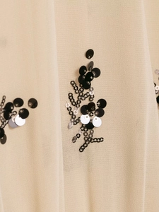 Close-up of sheer beige fabric with black and silver sequin floral embroidery detail