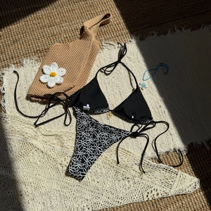 Close-up of black halter bikini top and daisy print bottoms on a summer resort mat