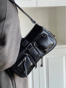 Detail of black cool girl faux leather shoulder bag with pockets and silver buckles