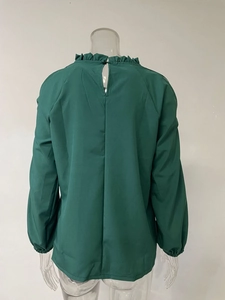 Détail du dos d'une blouse en mousseline vert foncé avec fermeture à bouton unique
