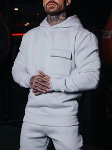 Detail of light grey cotton hoodie with chest flap pocket and ribbed cuffs on model