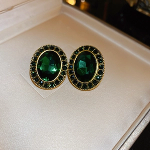 Détail macro de boucles d'oreilles ovales émeraude vintage avec bordure dorée