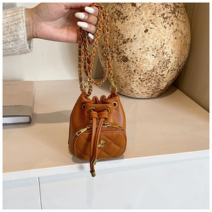 Detail of caramel mini bucket bag featuring camellia lock and quilted leather texture