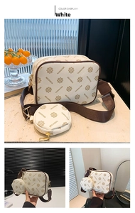 Detail view of white camera bag set with logo pattern and wide brown strap