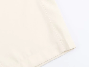 Dettaglio ravvicinato dei pantaloni crema a vita alta con finiture di cucitura a doppio ago