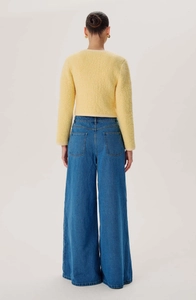 Rear view of light yellow fuzzy cardigan paired with high waist blue wide-leg denim jeans