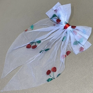 Detail view of white mesh bow hair clip featuring red sequin cherry embroidery patterns