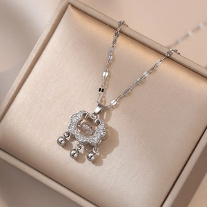 Detail of silver Ruyi lock pendant necklace with pavé zircons and dangling bells