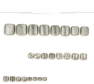 Detailed view of grey cat-eye press-on toenails with sparkling rhinestones and green gems