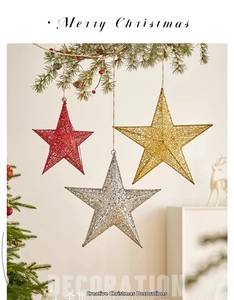 Close-up of glittery metal star ornaments hanging on pine branches for Christmas decor