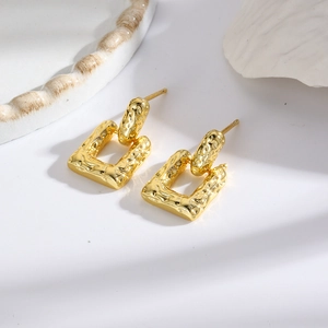 Detailed view of gold geometric drop earrings with vintage hammered metal texture finish