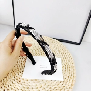 Detalle de diadema negra con nudos y brillantes pedrería sostenida en la mano