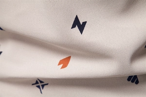 Dettaglio del tessuto piqué beige traspirante con stampa geometrica blu navy e arancione