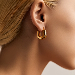 Close-up of gold-plated U-shaped hoop earrings with star engraving on a model