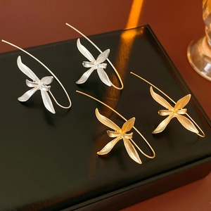 Detailed view of elegant gold and silver iris flower drop earrings on a black pedestal