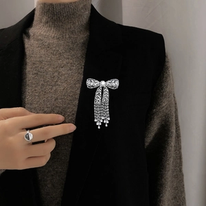 Nahaufnahme der eleganten Zirkon-Schleifenbrosche mit Quasten und Süßwasserperlen-Detail