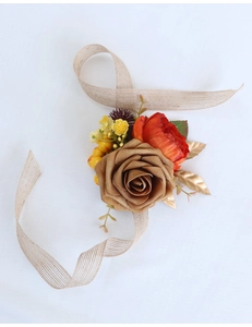 Detail of vintage autumn bridal wrist corsage with gold roses and orange faux flowers